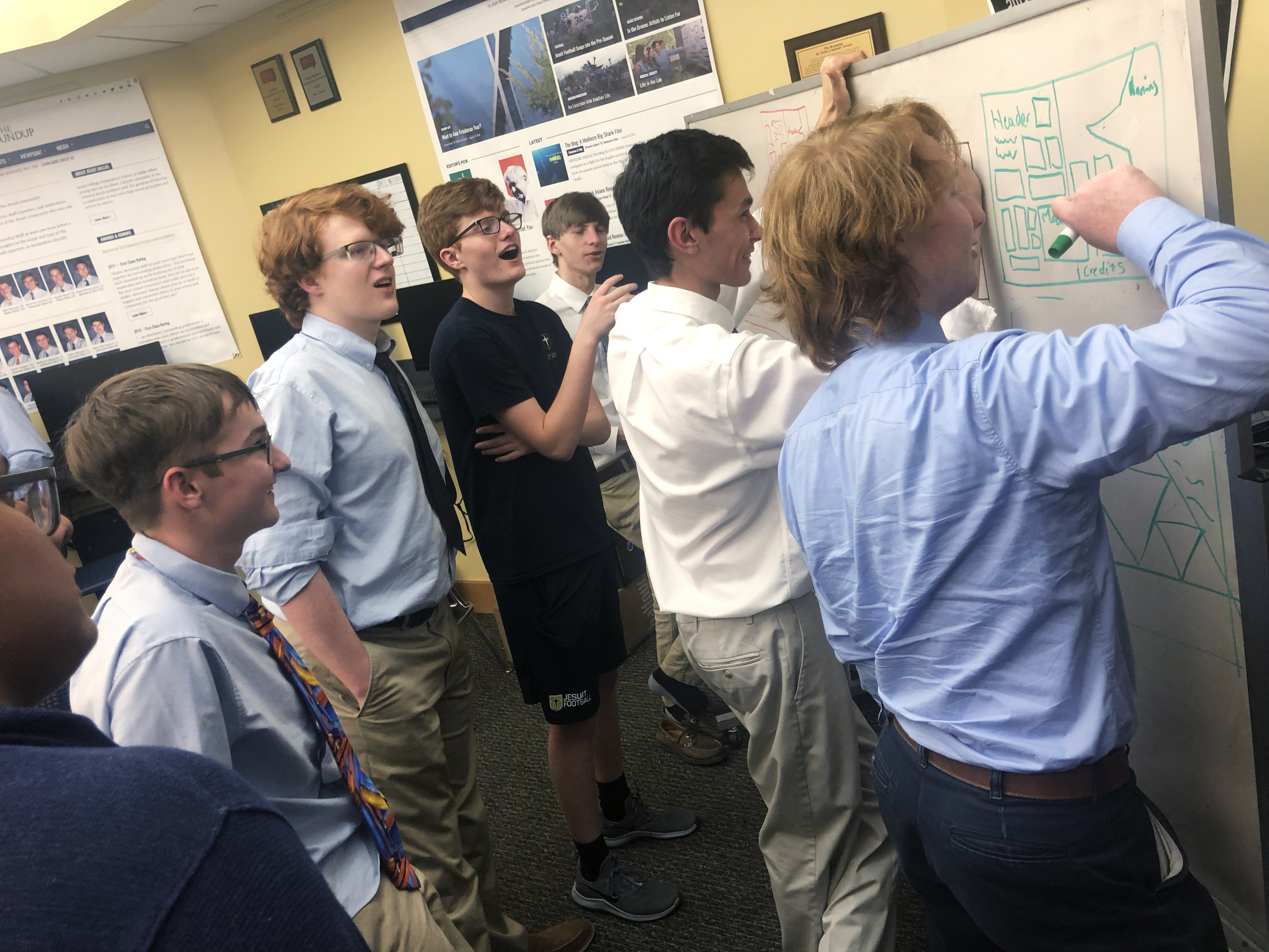 Students sketching ideas together on a whiteboard.
